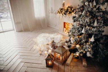 Beyaz bir odanın içinde Noel ağacı, süslü bir şömine, sallanan at ve yeni yıl hediyeleri olan bir oda.