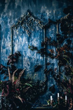 Kurumuş çiçekler, vazolar, avizeler, altın çerçeveli kumaşlar, lüks kraliyet tarzı ahşap bir masa, eski fenerlerle yanan mumlar.