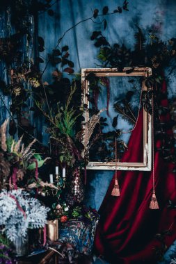 Kurumuş çiçekler, vazolar, avizeler, altın çerçeveli kumaşlar, lüks kraliyet tarzı ahşap bir masa, eski fenerlerle yanan mumlar.