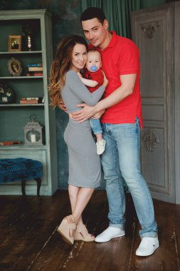 Stüdyoda bebekle poz veren mutlu ebeveynler.