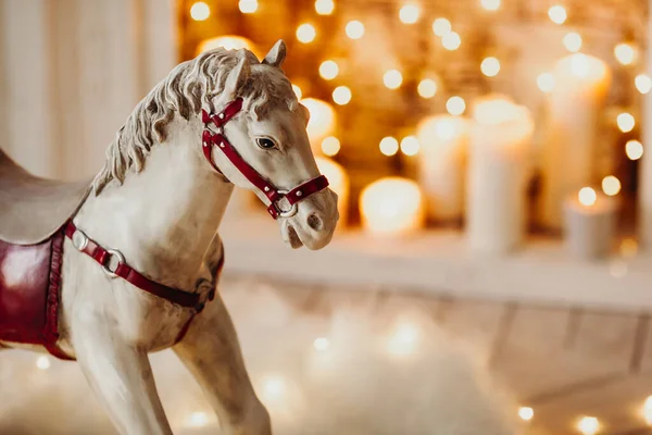 toy wooden rocking horse against the background of blurred lights in the fireplace