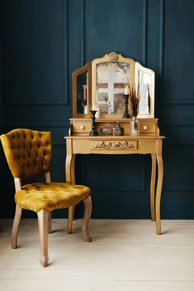 beautiful vintage colorful interior. classic room with wooden floor blue walls with moldings, dressing golden table with mirror decorated with elements and yellow chair