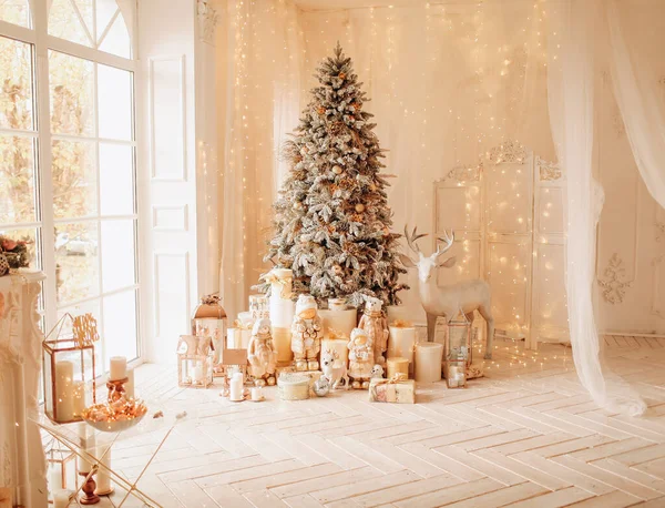 Noel iç tasarımında sıcak ve rahat bir sabah, ışıklarla süslenmiş Xmas ağacı hediyeler, oyuncaklar, geyikler, mumlar, fenerler, çelenkler, şöminenin içinde.