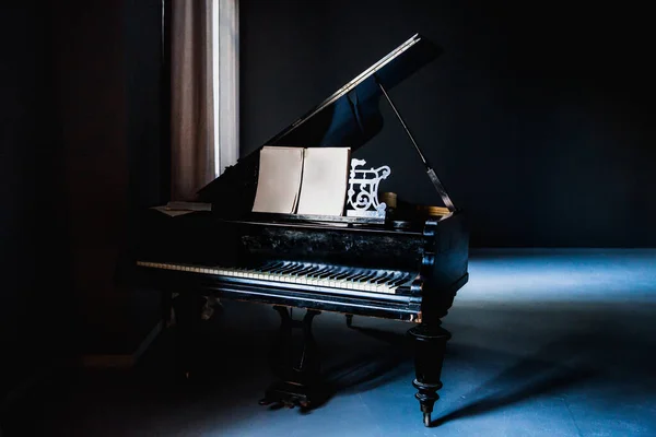 old black classical piano isolated in dark room