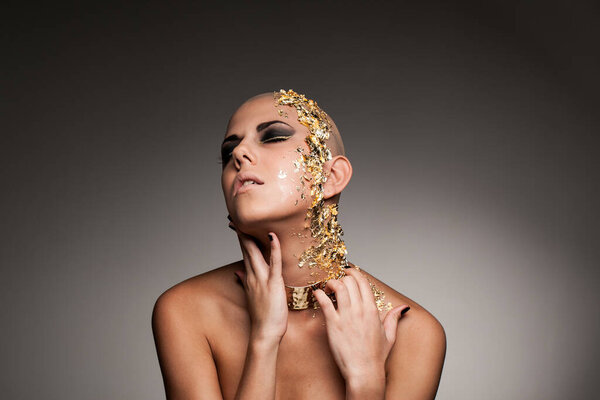 Portrait of bold and naked woman with gold elements