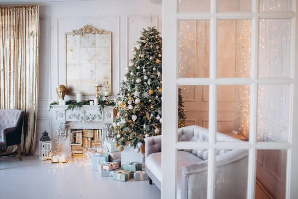 Noel ağacı ve dekoratif şömineyle süslenmiş, zarif, aydınlık renkte bir oda tasarımı.