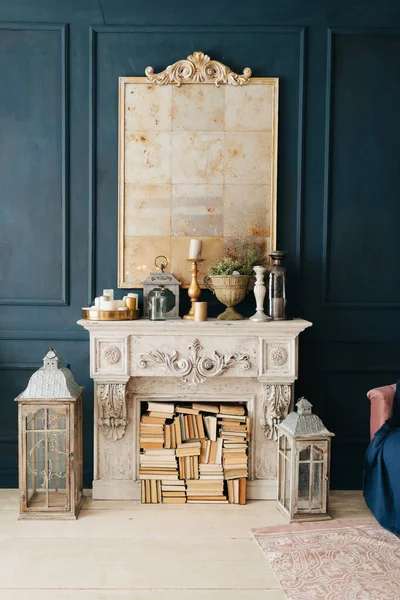 Güzel, renkli bir iç mekan. Klasik oda, ahşap döşemeli mavi duvarlar pervazlı, ayna ile süslenmiş altın masa, sarı sandalye, şömine, fener, pembe kanepe.