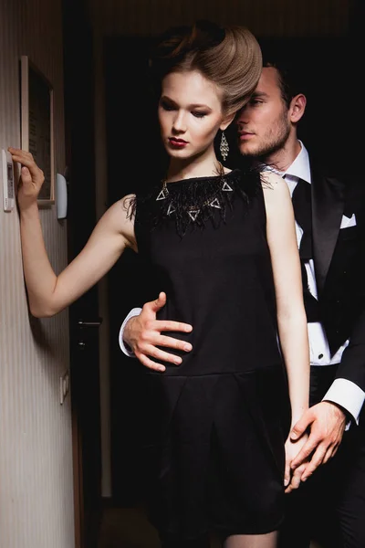 Güzel, tutkulu bir çift koridorda dikiliyor, bir adam bir kadına arkadan sarılıyor.
