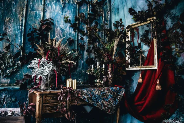 Kurumuş çiçekler, vazolar, avizeler, altın çerçeveli kumaşlar, lüks kraliyet tarzı ahşap bir masa, eski fenerlerle yanan mumlar.