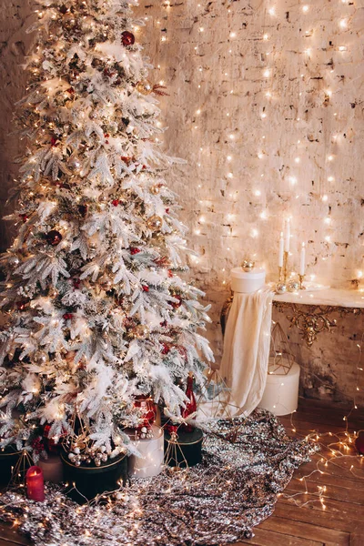 warm cozy evening luxury Christmas room interior design, Xmas tree decorated by gold lights presents gifts, candles, mirror garland lighting fireplace. holiday living room. New year holidays concept
