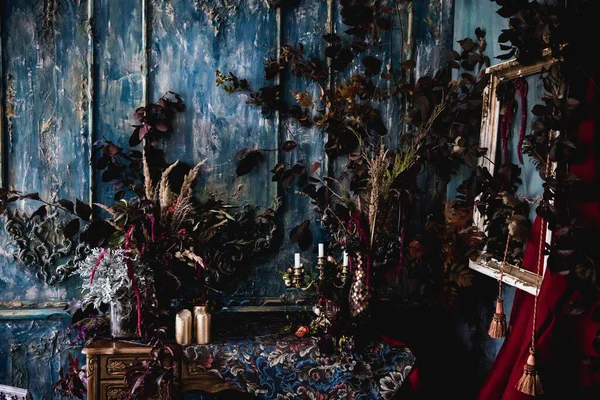 Kurumuş çiçekler, vazolar, avizeler, altın çerçeveli kumaşlar, lüks kraliyet tarzı ahşap bir masa, eski fenerlerle yanan mumlar.