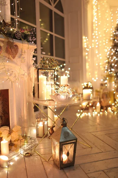 Noel iç tasarımında sıcak ve sıcak bir akşam, ışıklarla süslenmiş Xmas ağacı hediyeler, oyuncaklar, geyikler, mumlar, fenerler, kapalı alanda yanan şömine. tatil salonu sihirli yeni yıl