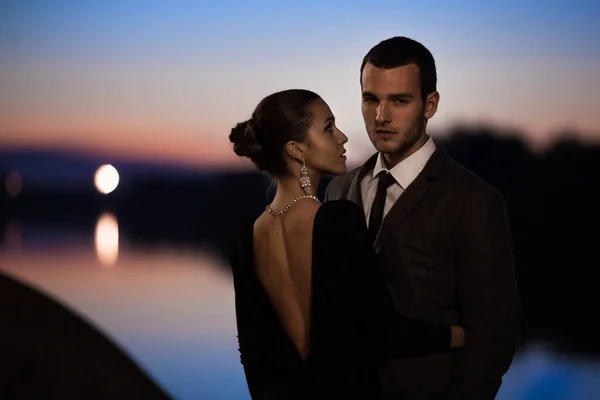 Çekici bir çift şık kıyafetler giyip geceleri dışarıda sarılıyorlar. 