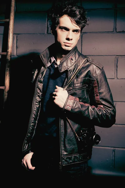Duvarın yanında duran deri ceketli yakışıklı manken.