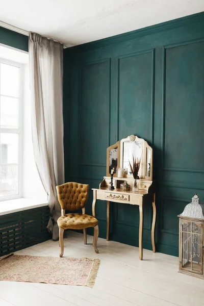 beautiful vintage colorful interior. classic room with wooden floor green walls with moldings, dressing golden table with mirror decorated with elements, yellow chair