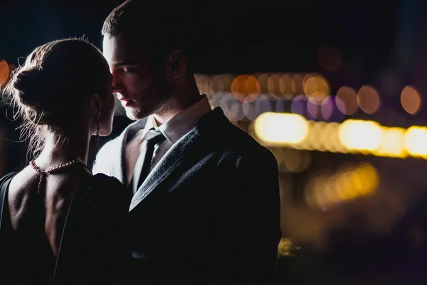 Çekici bir çift şık kıyafetler giyip geceleri dışarıda sarılıyorlar. 