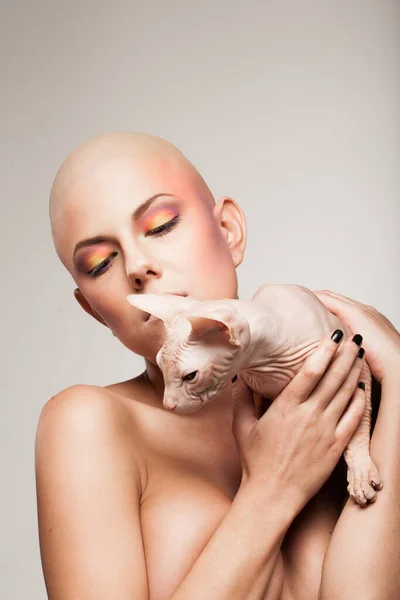 bald woman model with cat on light background