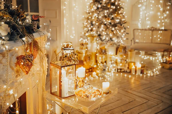 Noel iç tasarımında sıcak ve sıcak bir akşam, ışıklarla süslenmiş Xmas ağacı hediyeler, oyuncaklar, geyikler, mumlar, fenerler, kapalı alanda yanan çelenkler.