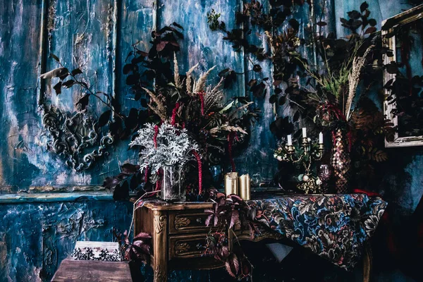 Kurumuş çiçekler, vazolar, avizeler, altın çerçeveli kumaşlar, lüks kraliyet tarzı ahşap bir masa, eski fenerlerle yanan mumlar.