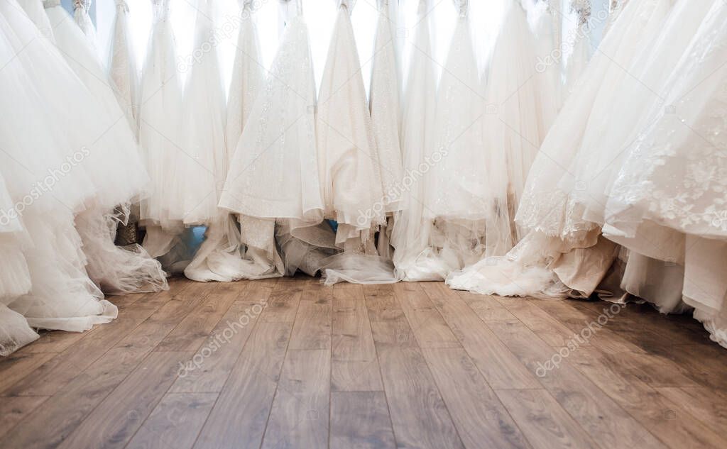 beautiful white wedding dresses on hangers in the store