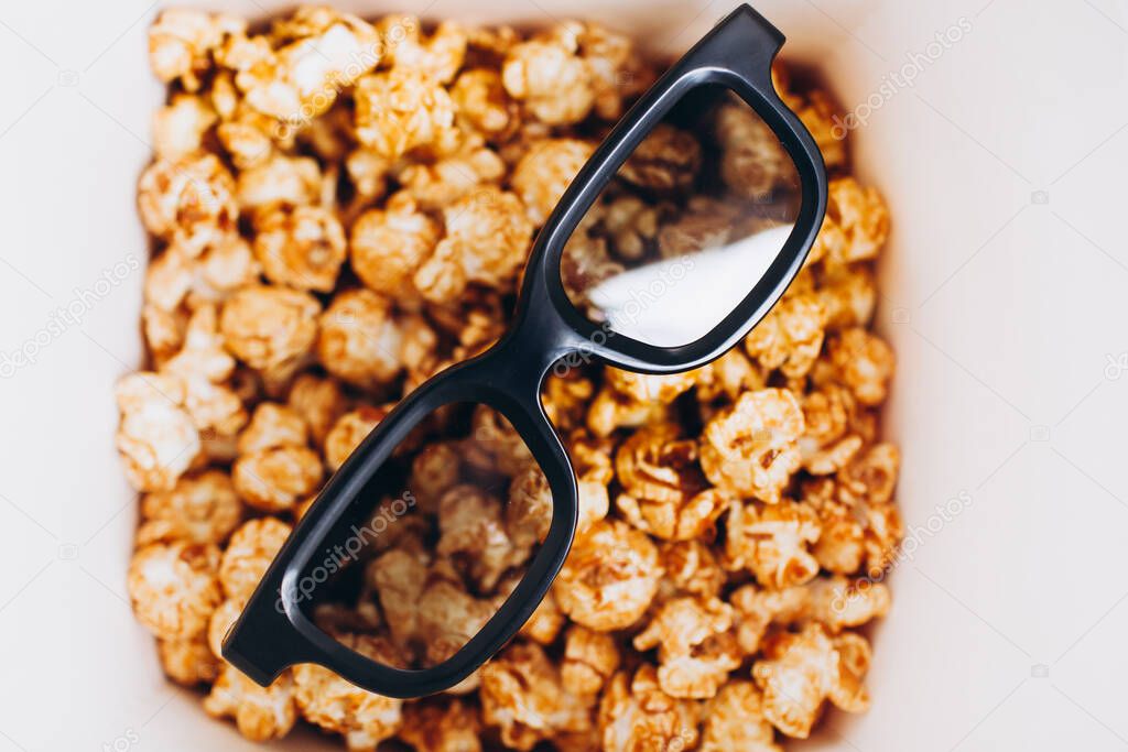 banner black glasses for watching 3D movies in a movie theater are in a box of sweet popcorn. cinema rest entertainment copy space place text