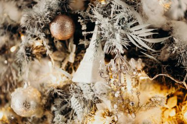 Noel ağacındaki klasik Noel ağacı oyuncaklarının yakın plan fotoğrafı. Altın rengi süslemeler, çelenk ışıkları. Mutlu yıllar ve Noel