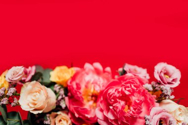 Kırmızı arka planda renkli çiçekleri olan güzel bir buket.