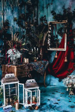 Kurumuş çiçekler, vazolar, avizeler, altın çerçeveli kumaşlar, lüks kraliyet tarzı ahşap bir masa, eski fenerlerle yanan mumlar.