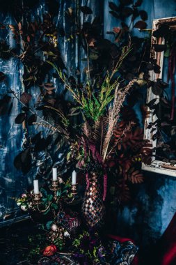 Kurumuş çiçekler, vazolar, avizeler, altın çerçeveli kumaşlar, lüks kraliyet tarzı ahşap bir masa, eski fenerlerle yanan mumlar.