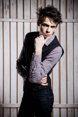 Stüdyoda poz veren gömlekli ve yelekli yakışıklı bir adam.