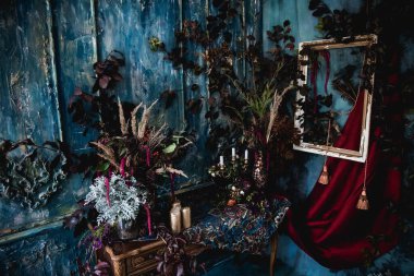 Kurumuş çiçekler, vazolar, avizeler, altın çerçeveli kumaşlar, lüks kraliyet tarzı ahşap bir masa, eski fenerlerle yanan mumlar.