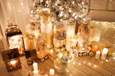 Noel iç tasarımında sıcak ve sıcak bir akşam, ışıklarla süslenmiş Xmas ağacı hediyeler, oyuncaklar, geyikler, mumlar, fenerler, kapalı alanda yanan şömine. tatil salonu sihirli yeni yıl