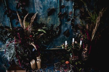 Kurumuş çiçekler, vazolar, avizeler, altın çerçeveli kumaşlar, lüks kraliyet tarzı ahşap bir masa, eski fenerlerle yanan mumlar.