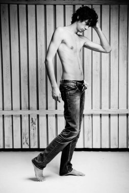 Üstsüz, baştan çıkarıcı yakışıklı model stüdyoda poz veriyor.