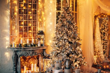 Noel iç tasarımında sıcak ve sıcak bir akşam, ışıklarla süslenmiş Xmas ağacı hediyeler, oyuncaklar, geyikler, mumlar, fenerler, kapalı alanda yanan çelenkler.