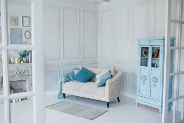 Kanepesi ve doğal renklerde yastıkları olan parlak oturma odası. Mavi ekose ve İskandinav tarzında gardırop.