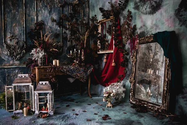 Kurumuş çiçekler, vazolar, avizeler, altın çerçeveli kumaşlar, lüks kraliyet tarzı ahşap bir masa, eski fenerlerle yanan mumlar.