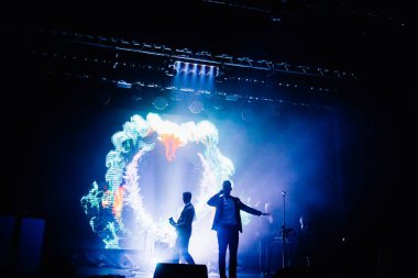 Parlak spot ışıklarının kırmızı mavi ışıklarıyla sahnede şarkı söyleyen şarkıcı ve rock grubunun bulanık renkli fotoğrafı