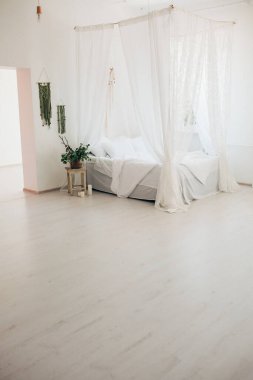 Minimalist İskandinav tarzı bir yatak odasında rahat bir yatak odası, örtülü yatak, battaniye yastıkları, bitki. Günaydın güneşli fotoğraf.