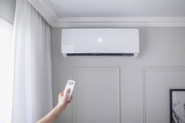 Odanın içinde güzel bir odada uzaktan kumandalı bir klima ve gri bir duvar var.