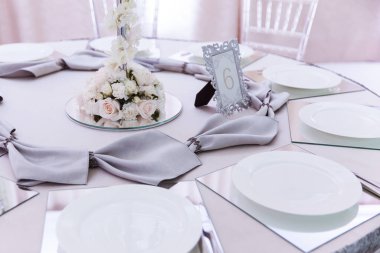resmi lüks düğün dekorasyonu masaları beyaz masa örtüsü, tabaklar, menüler, bardaklar, vazolar, orkideler, mumlar gümüş koltuklar, mavi arka plan