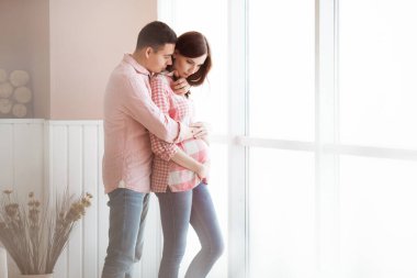 Müstakbel anne babalar aydınlık bir panorama penceresinin arkasında durur.