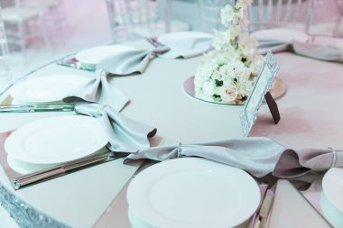 resmi lüks düğün dekorasyonu masaları beyaz masa örtüsü, tabaklar, menüler, bardaklar, vazolar, orkideler, mumlar gümüş koltuklar, mavi arka plan