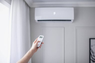 Odanın içinde güzel bir odada uzaktan kumandalı bir klima ve gri bir duvar var.