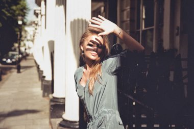 Güzel bir kadın güneşli bir günde sokakta gölgesini yapıyor.