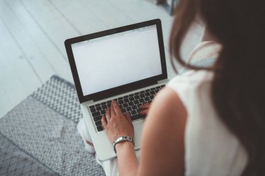 Beyaz arkaplanı olan gümüş dizüstü bilgisayarda yazan kadın.