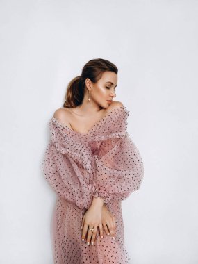 Beyaz arka planda pembe elbiseli güzel sarışın manken.