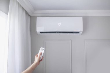 Odanın içinde güzel bir odada uzaktan kumandalı bir klima ve gri bir duvar var.