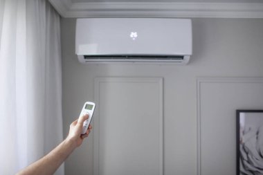 Odanın içinde güzel bir odada uzaktan kumandalı bir klima ve gri bir duvar var.