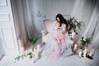 Anne ve sevimli kız stüdyoda pembe elbiseler içinde.